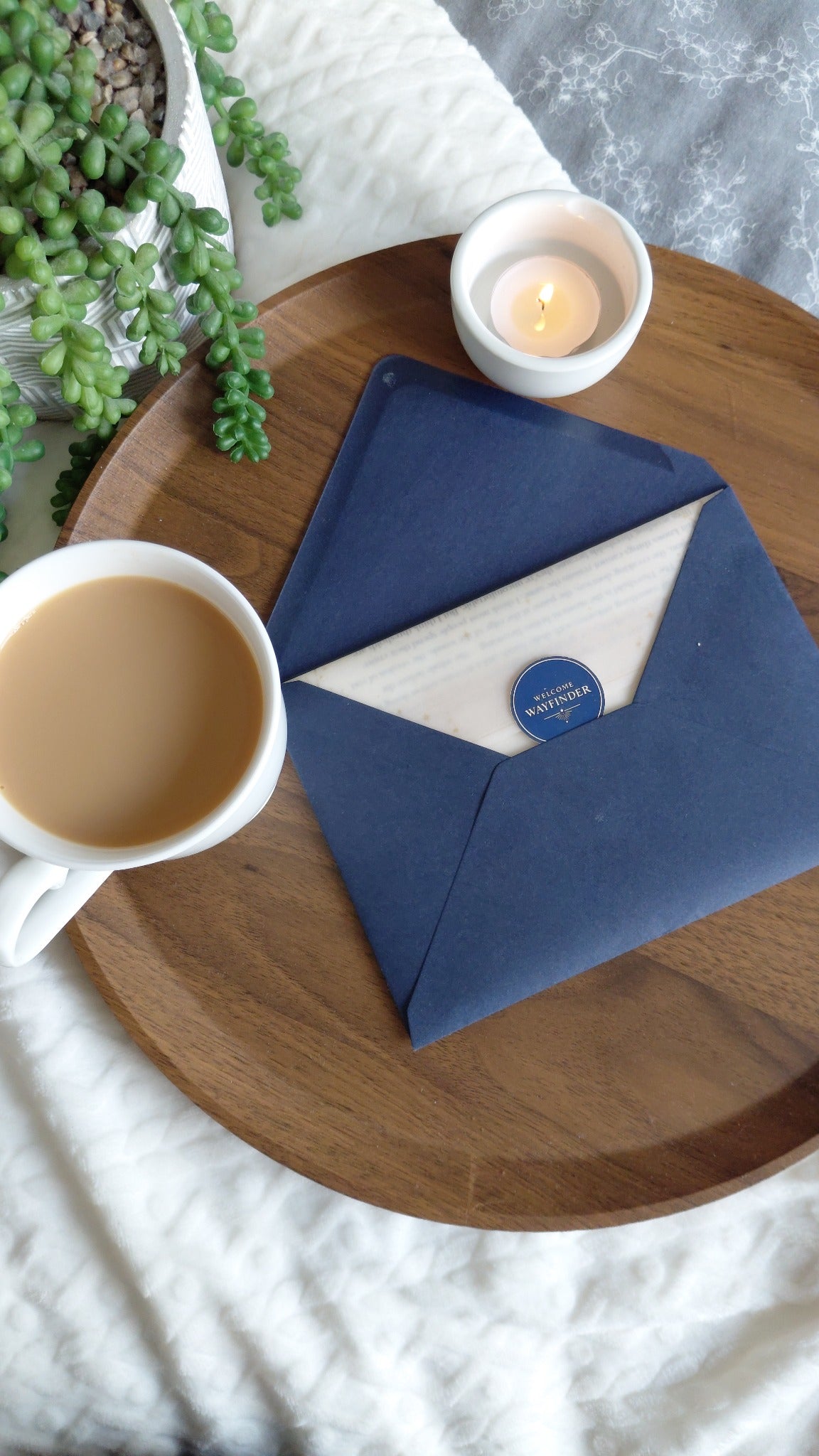 Atlas correspondence beside a cup of tea and candle